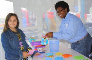 Natalie Procksell, 10, of Newnan, puts the finishing touches on her craft with a little help from EMC Customer Service Representative Dawn Williams.